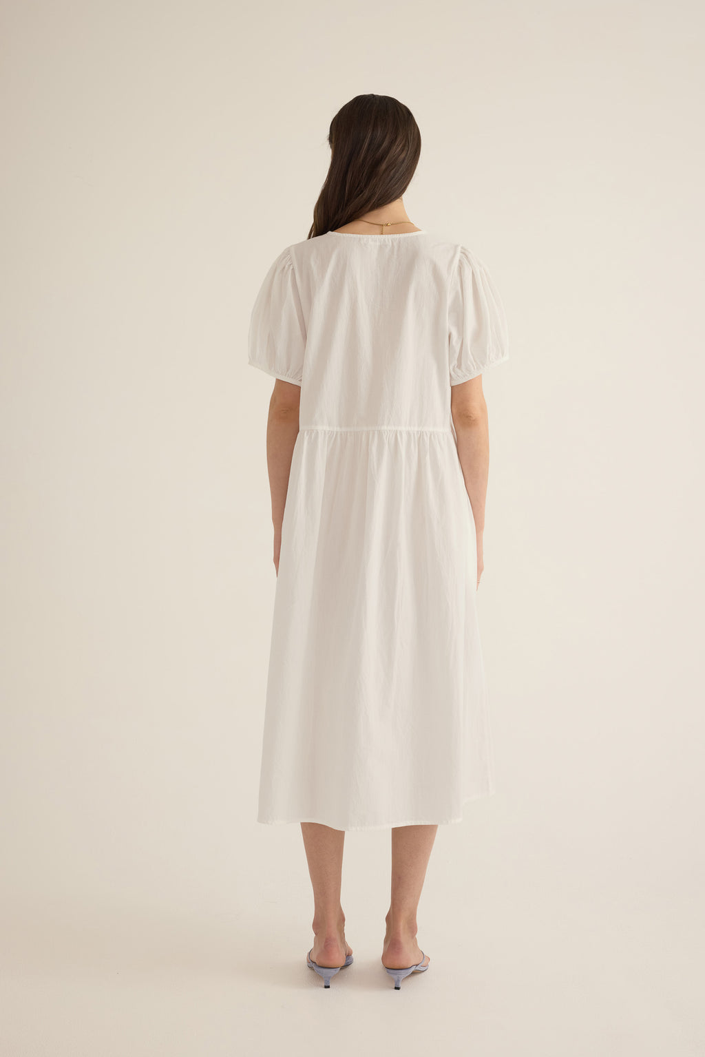 Back view of model wearing the Amelie organic cotton v-lace midi dress in ivory