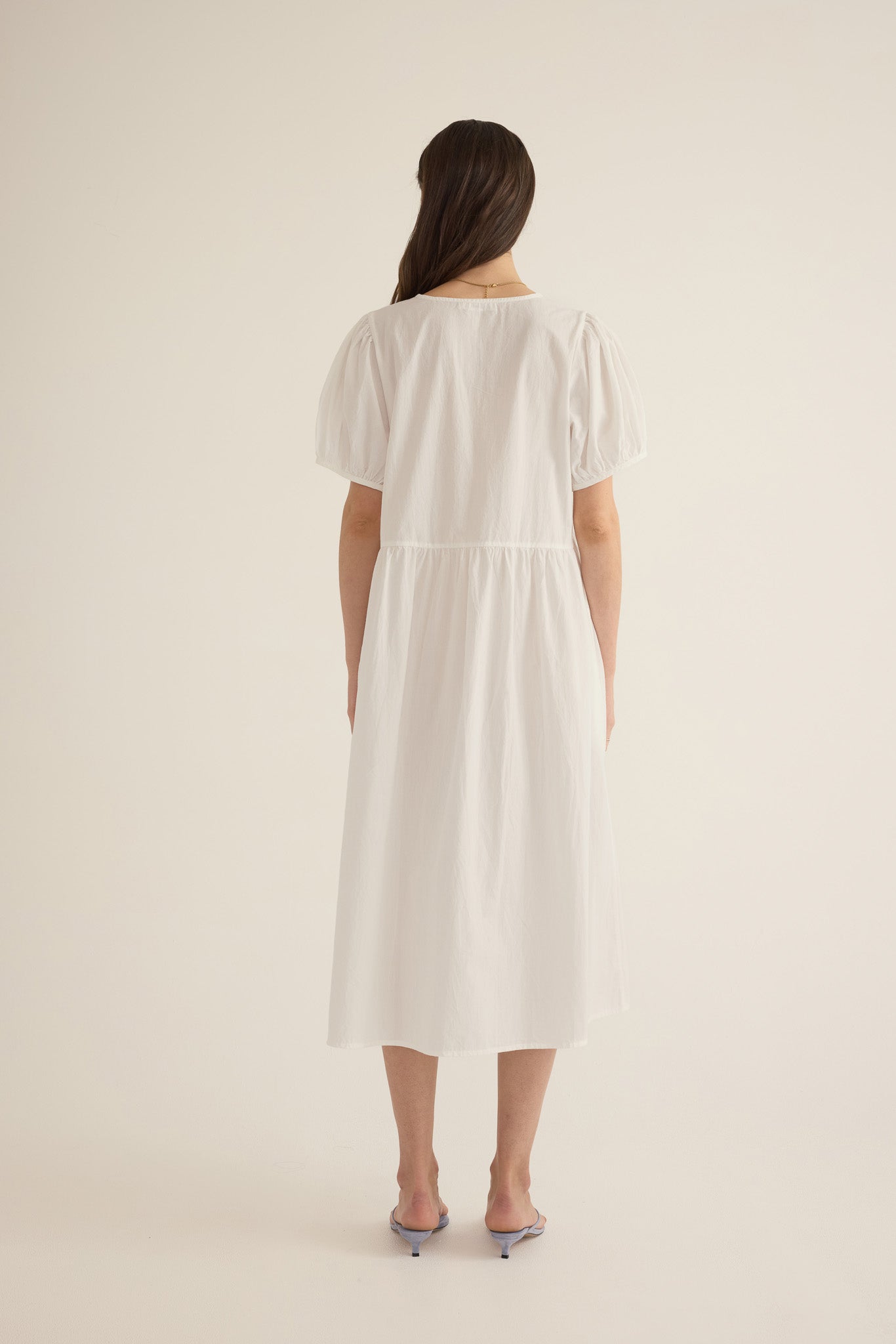 Back view of model wearing the Amelie organic cotton v-lace midi dress in ivory