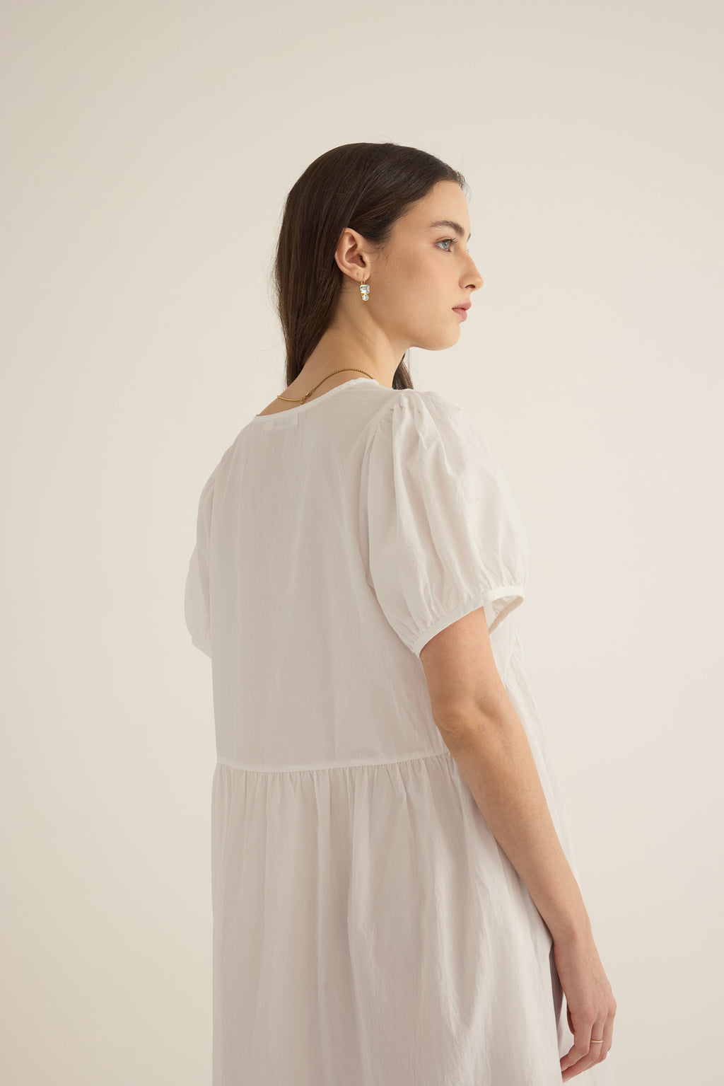 Front side closeup view of model wearing the Amelie organic cotton v-lace midi dress in ivory, showing puff sleeve and dropped waist seam detail