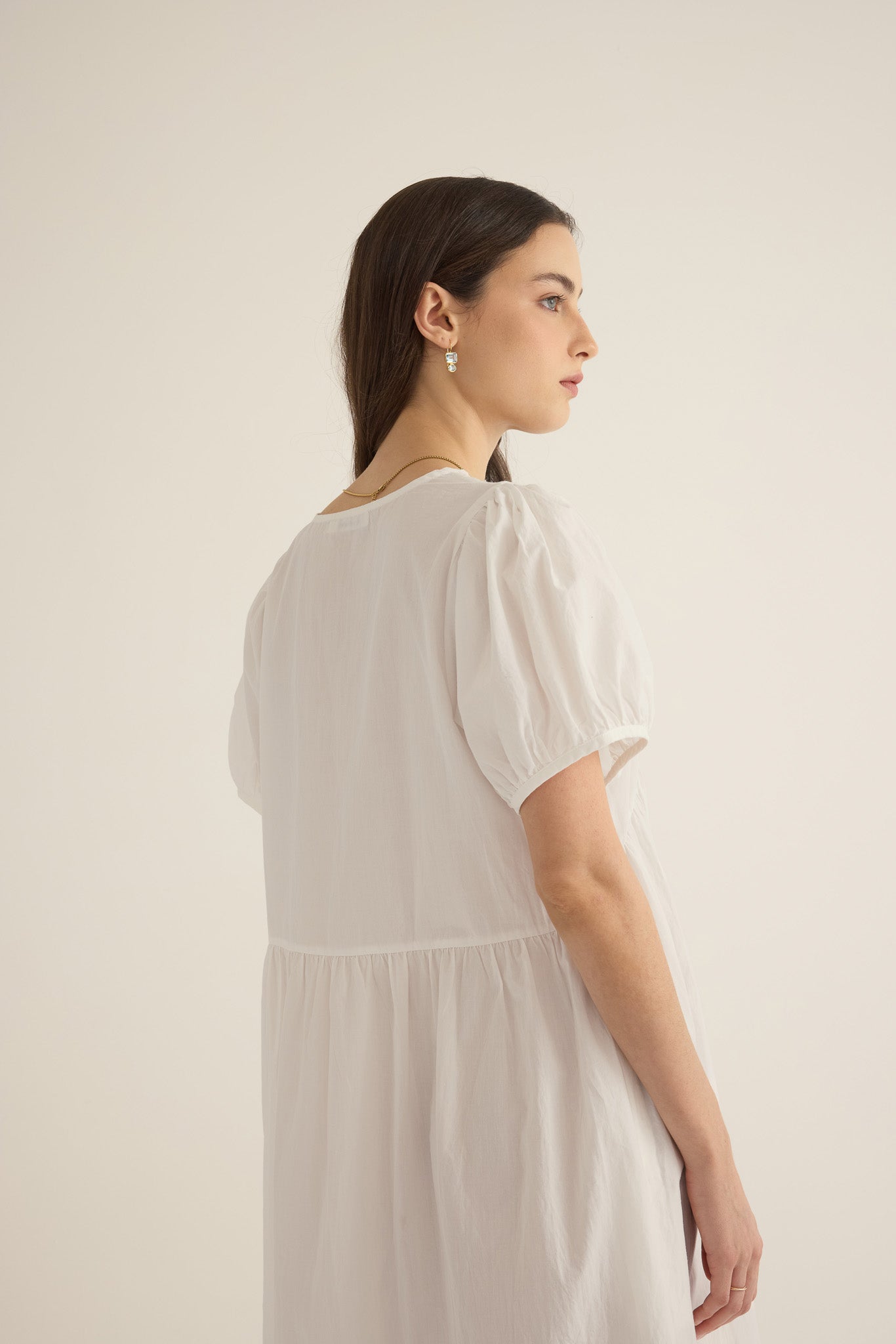 Front side closeup view of model wearing the Amelie organic cotton v-lace midi dress in ivory, showing puff sleeve and dropped waist seam detail