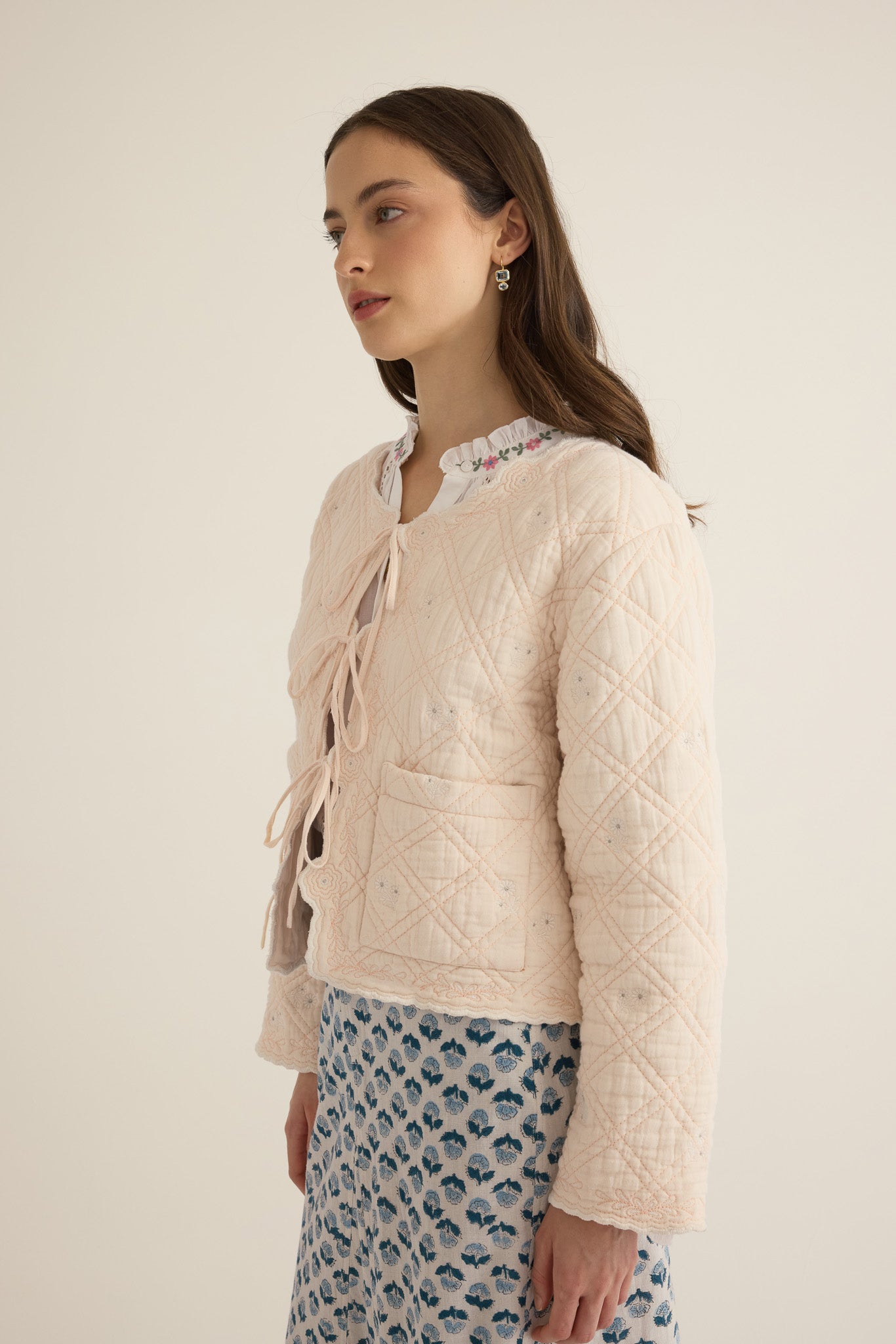 Closeup side view of model wearing the Anais Organic Cotton Quilted Jacket with Ties in rosewater pale pink, showing the sleeve