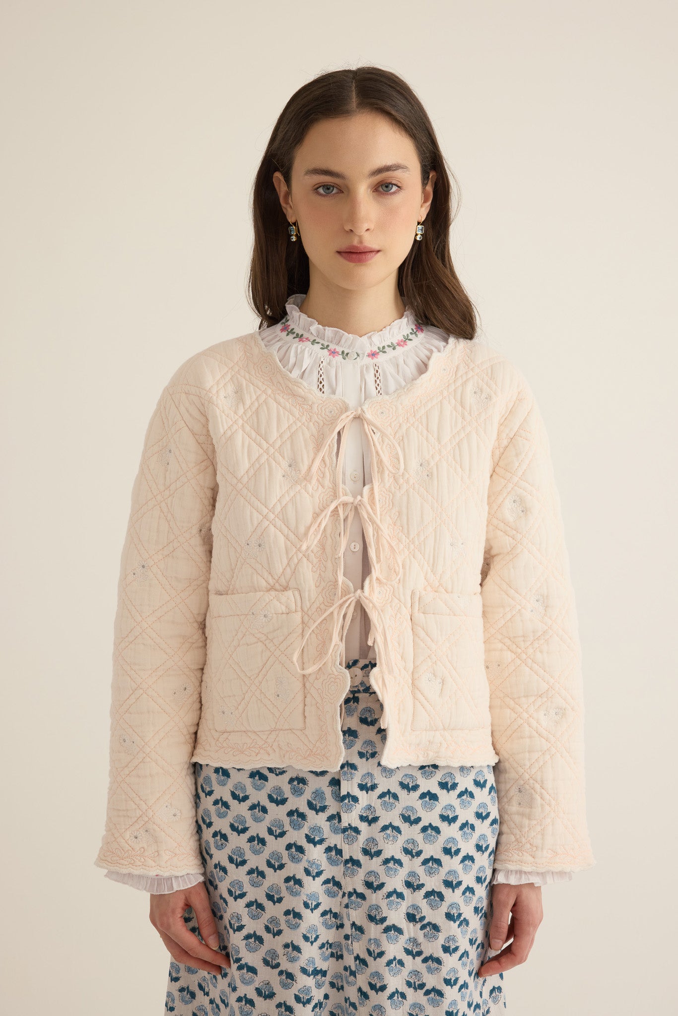 Front closeup view of model with hands loose wearing the Anais Organic Cotton Quilted Jacket with Ties in rosewater pale pink