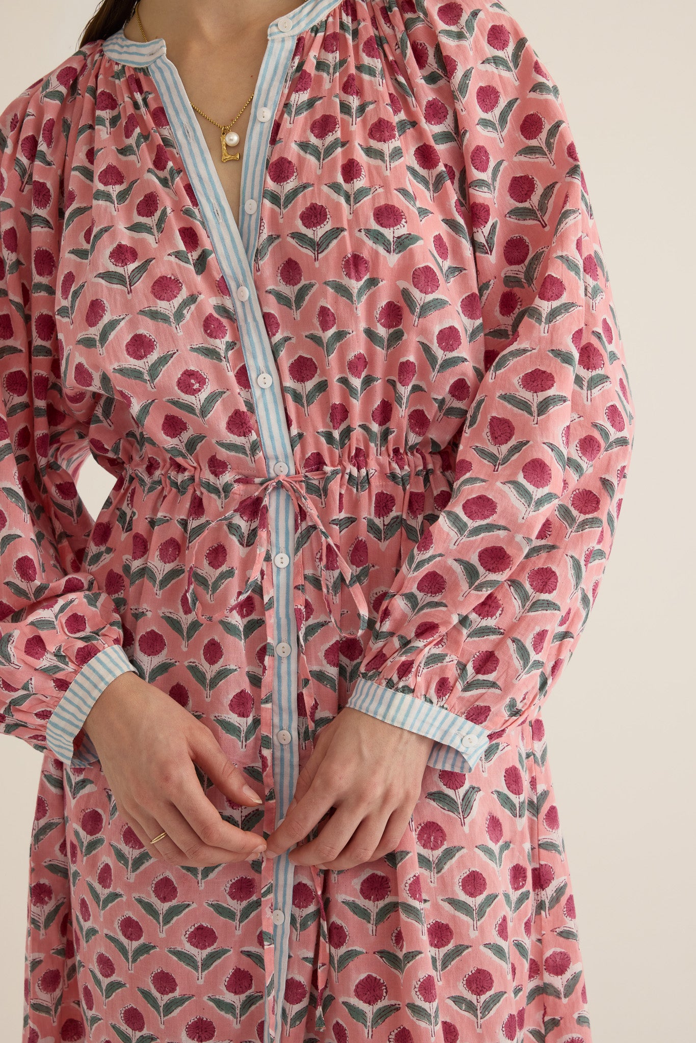 Front closeup view of model wearing the Juliet Block Printed Cotton Drop Sleeve Raglan Shirt Dress in Pink Dahlia, showing the mother of pearl buttoned front and waist tie