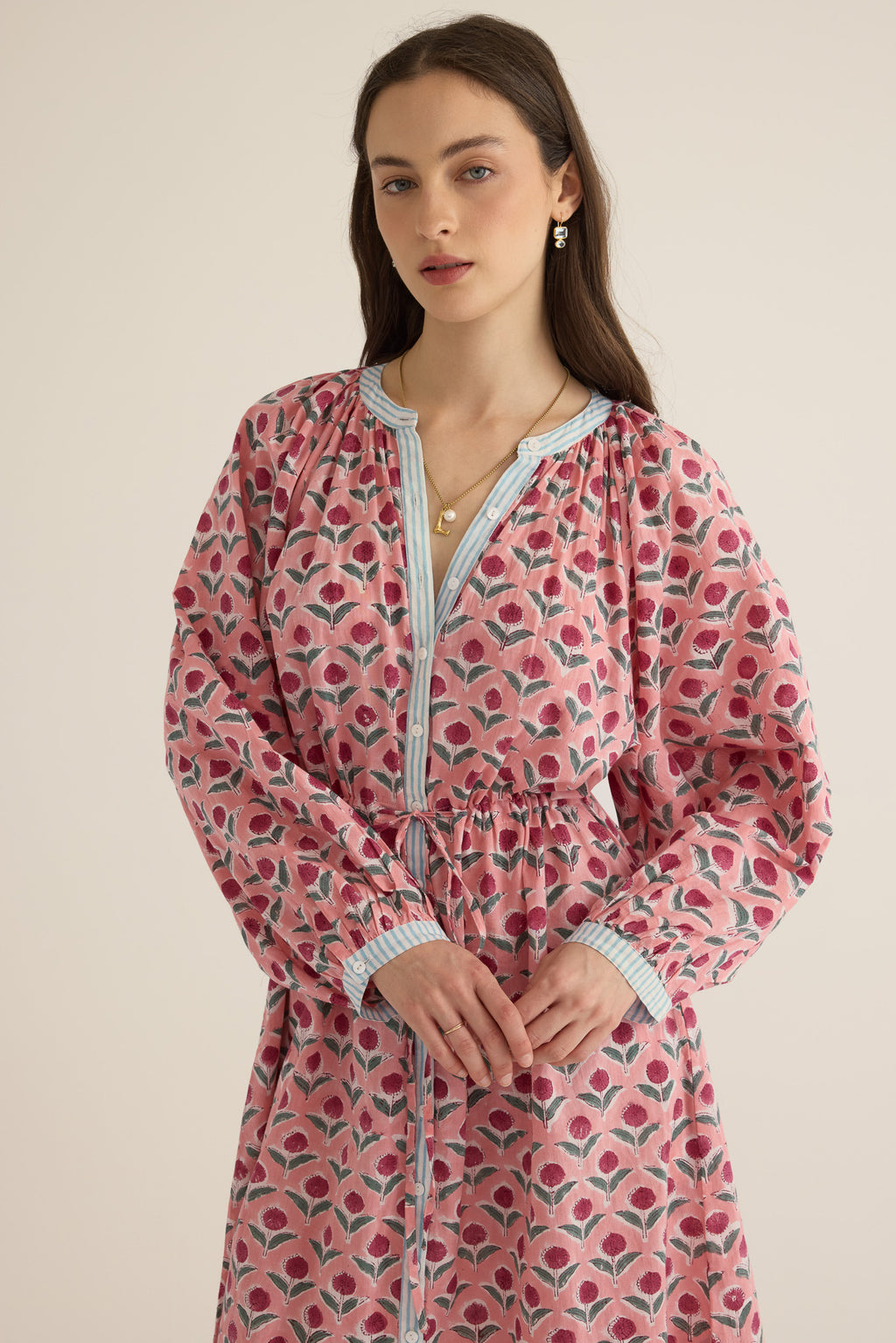 Front closeup view of model wearing the Juliet Block Printed Cotton Drop Sleeve Raglan Shirt Dress in Pink Dahlia, with her hands folded at the waist