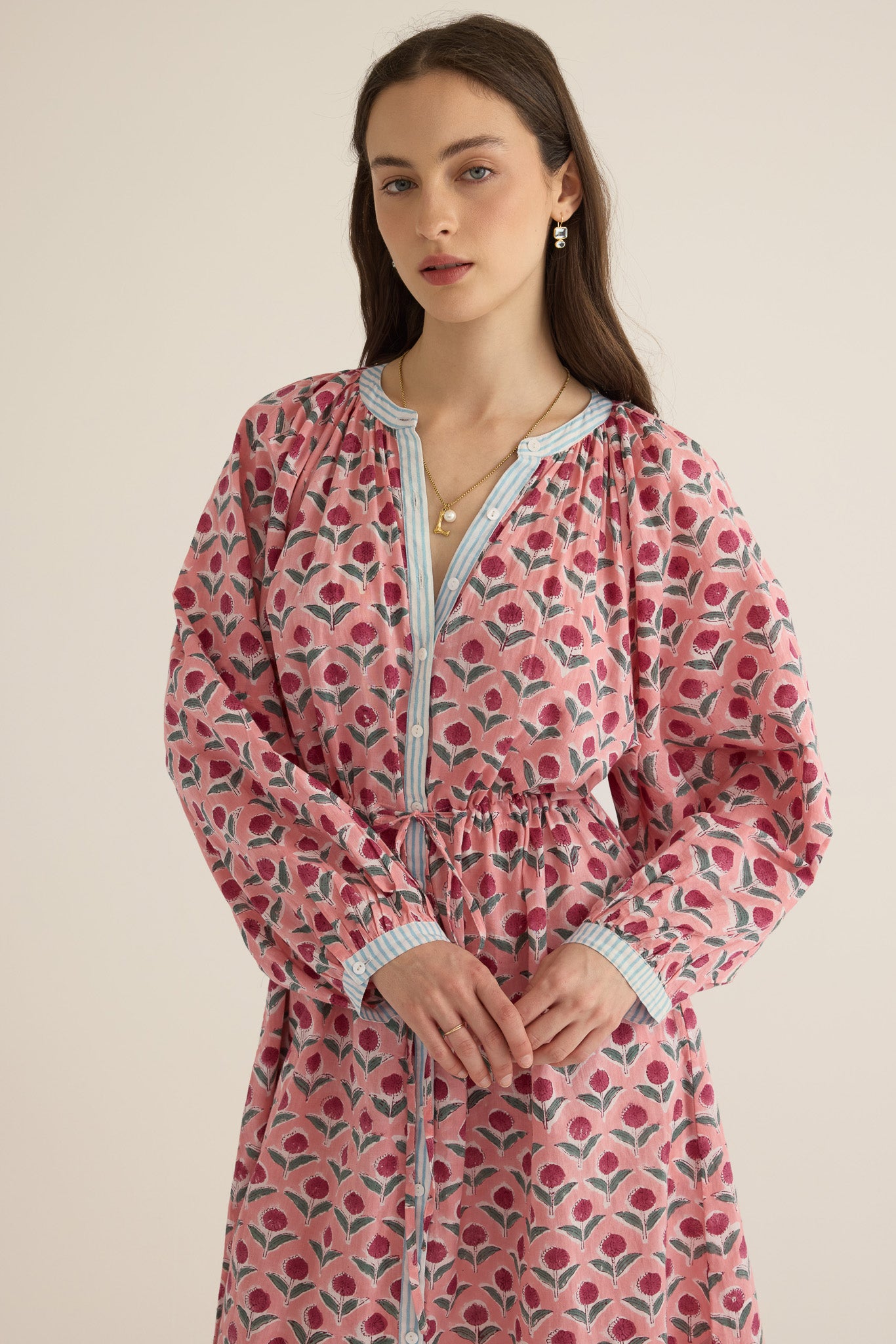 Front closeup view of model wearing the Juliet Block Printed Cotton Drop Sleeve Raglan Shirt Dress in Pink Dahlia, with her hands folded at the waist
