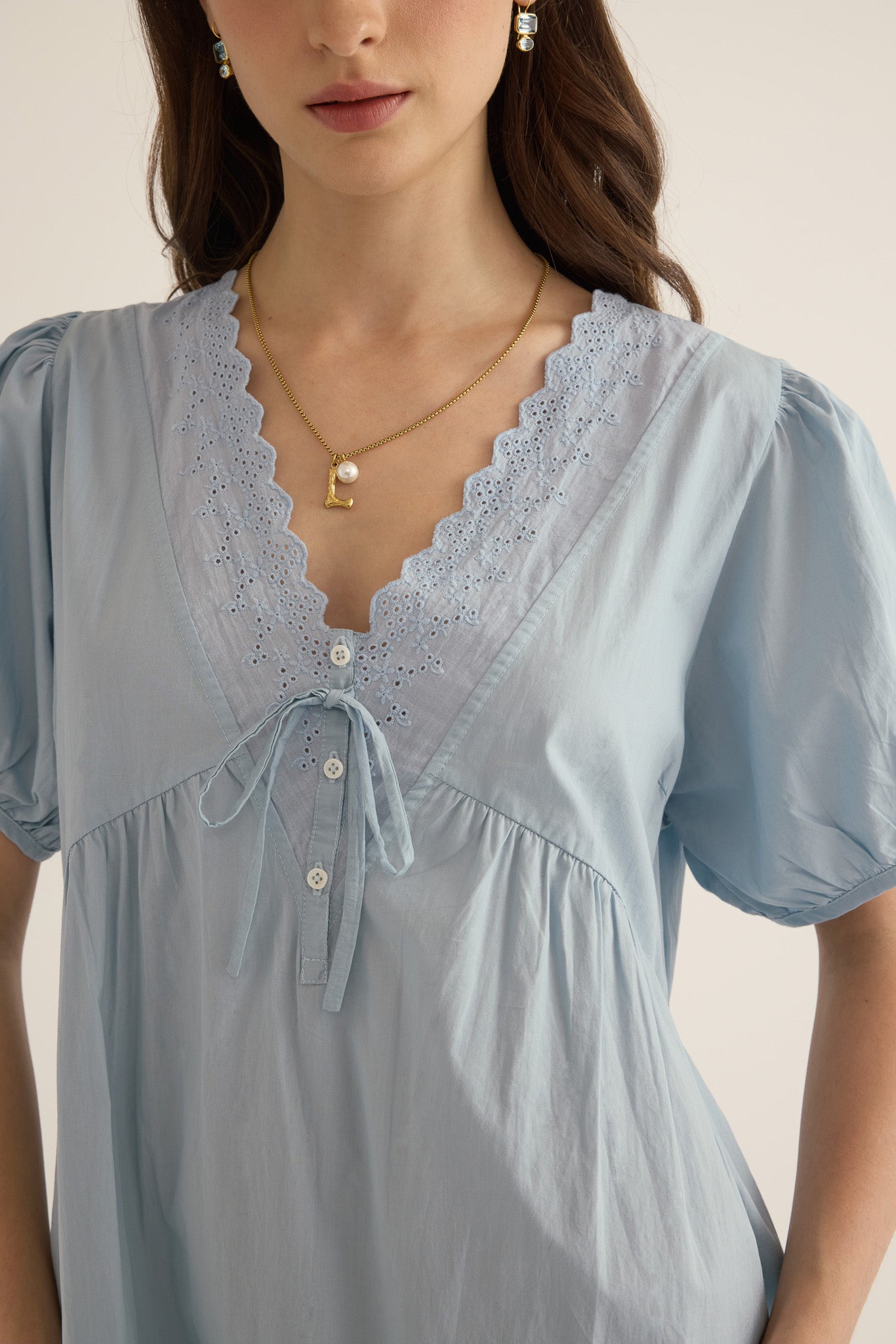 Close up detail of model wearing the Amelie organic cotton v-lace midi dress in forget me not pale blue.