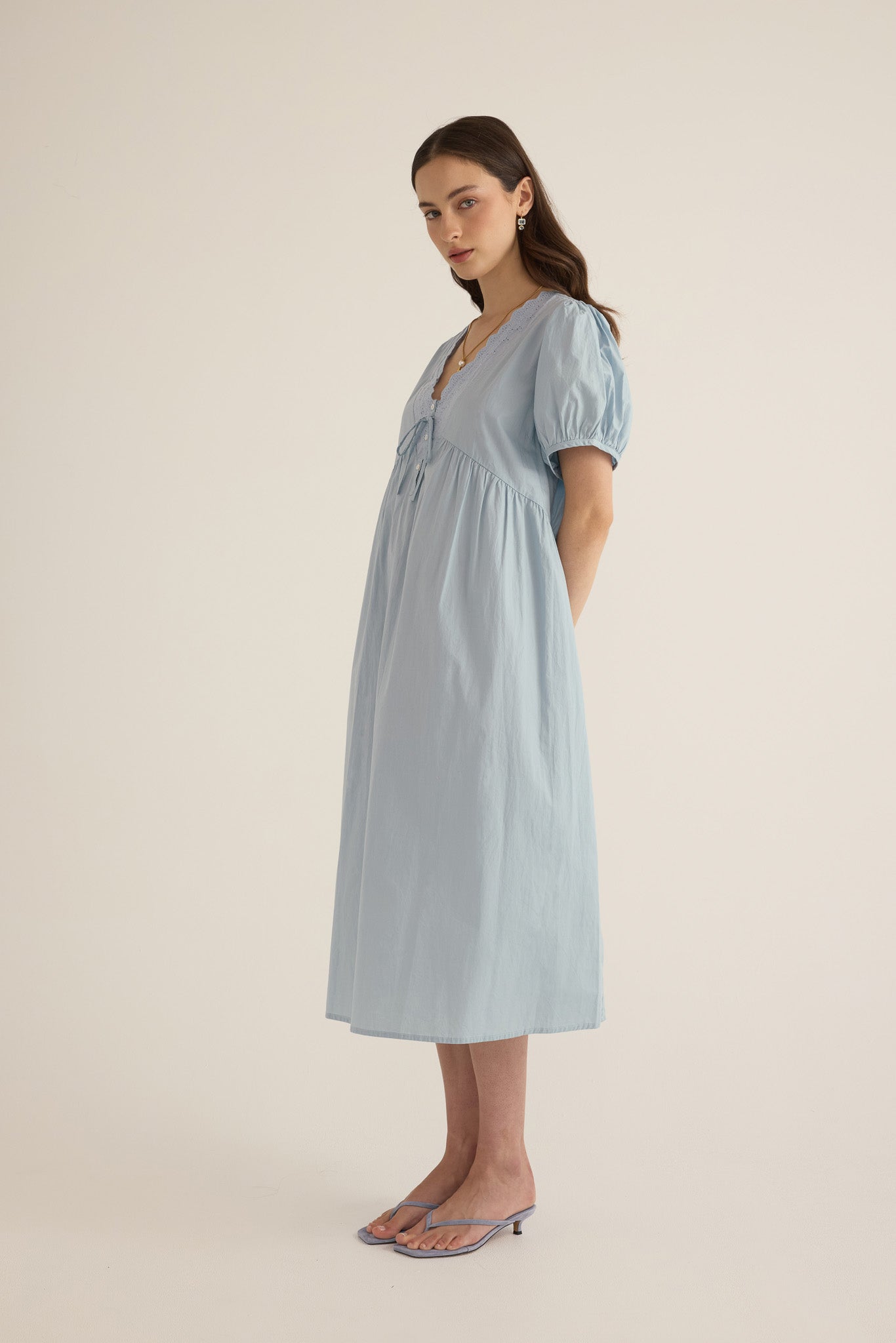 Side view of model wearing the Amelie organic cotton v-lace midi dress in forget me not pale blue.