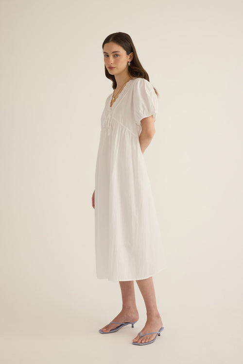 Side view of model wearing the Amelie organic cotton v-lace midi dress in ivory