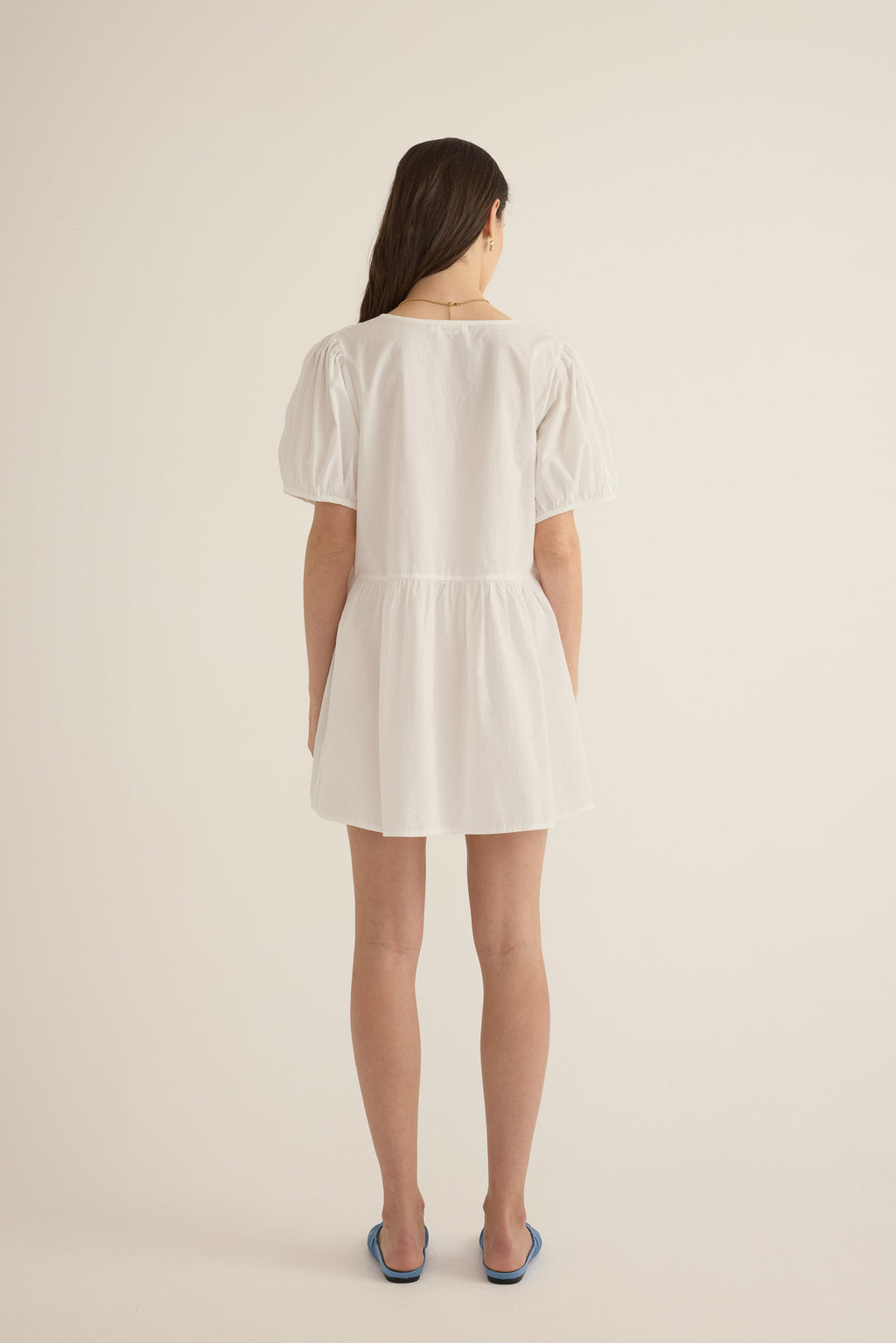 Back view of model wearing the Amelie organic cotton v-lace short dress in ivory.