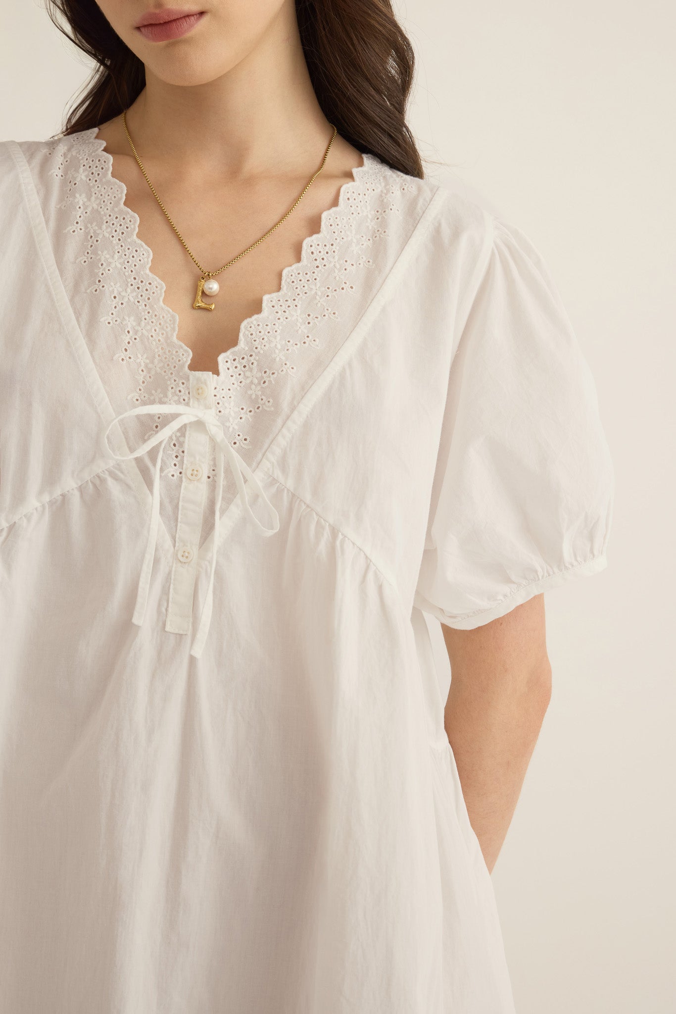 Close up of model wearing the Amelie organic cotton v-lace short dress in ivory.