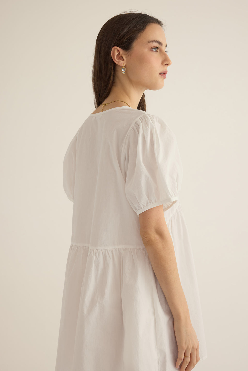 Side view of model wearing the Amelie organic cotton v-lace short dress in ivory.