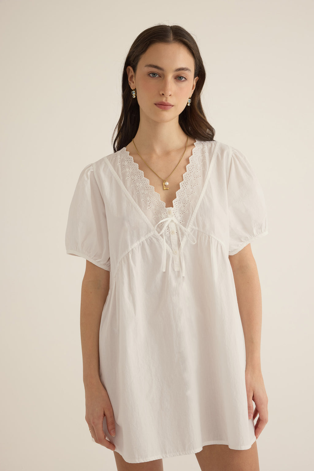 Close up of model wearing the Amelie organic cotton v-lace short dress in ivory.