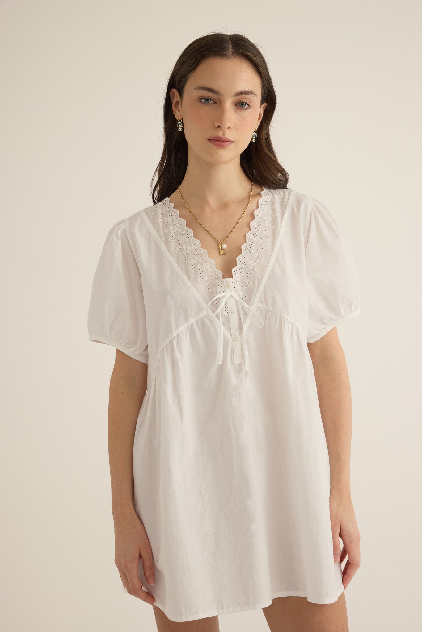 Close up of model wearing the Amelie organic cotton v-lace short dress in ivory.
