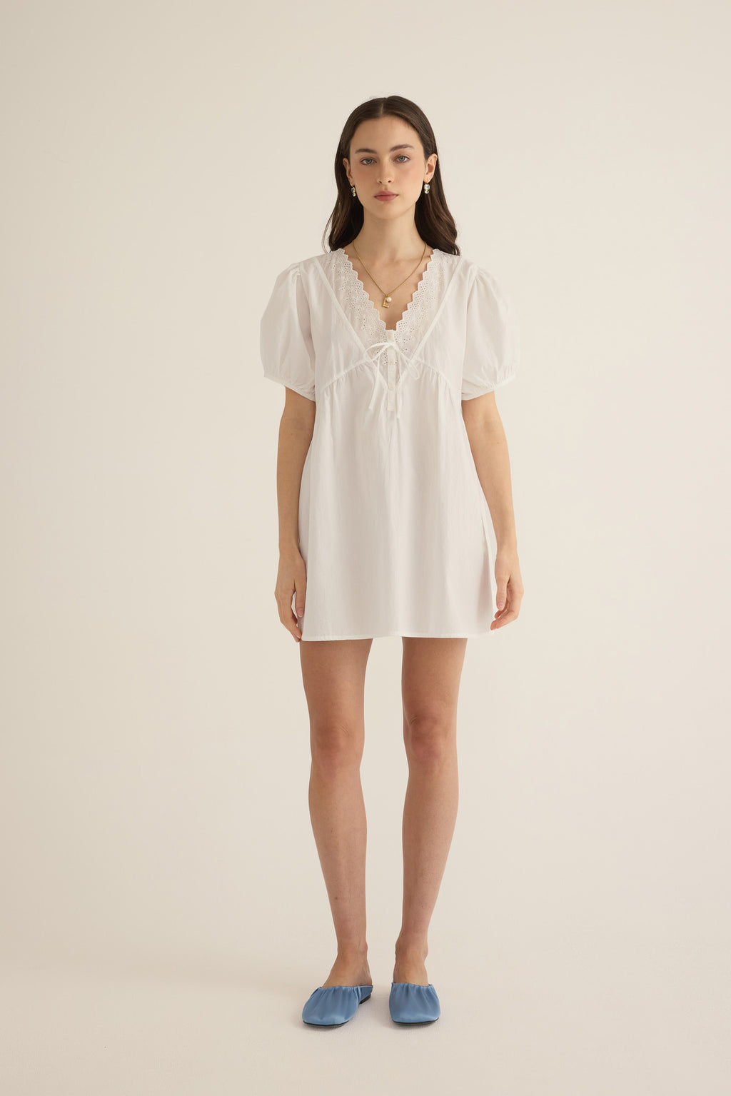 Model wears the Amelie organic cotton v-lace short dress in ivory.