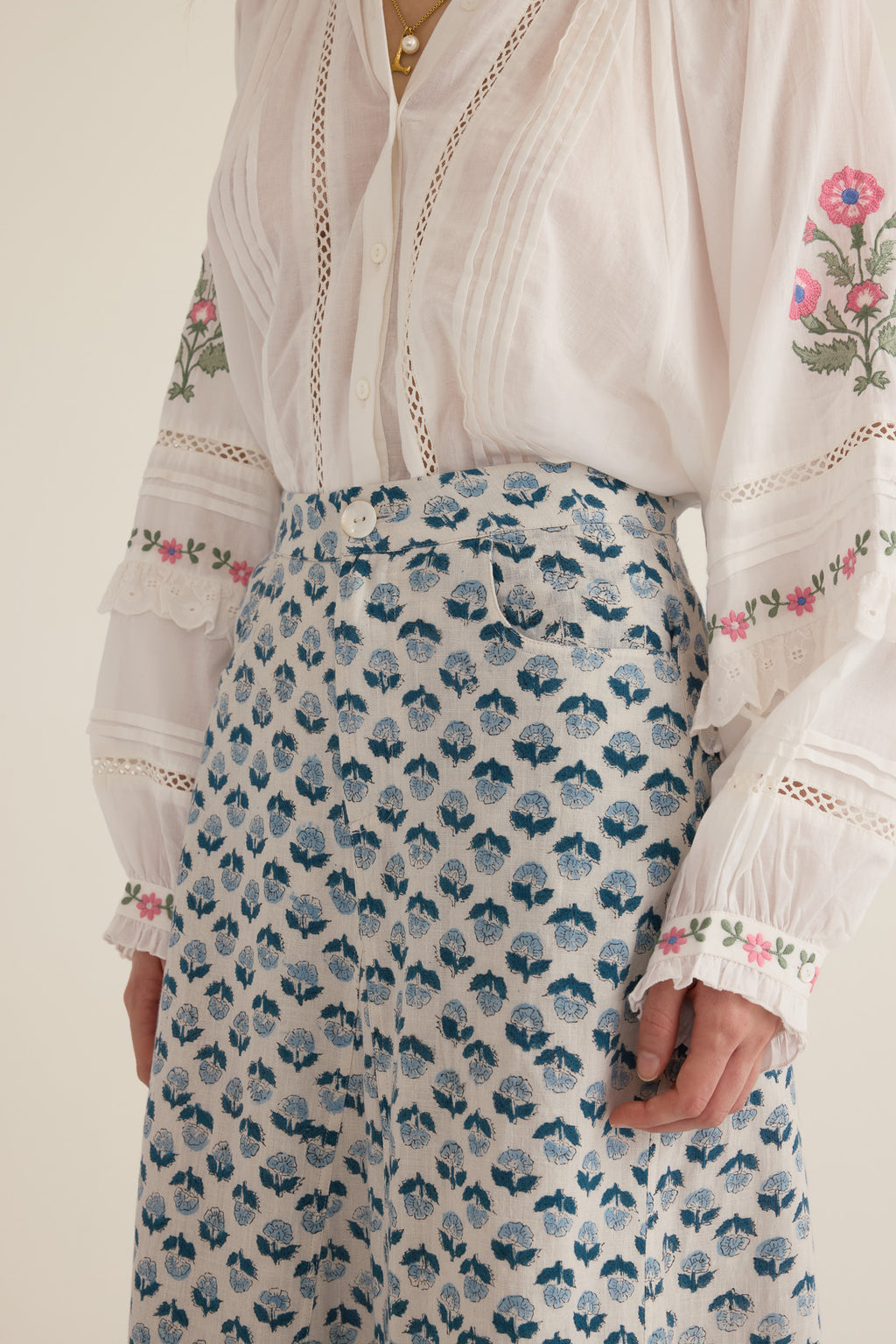 Closeup view of model wearing the Joni Block Printed Cotton A-Line Midi Skirt in Blue Gardenia with the Juliet Embroidered Raglan Drop Sleeve Blouse in Ivory, showing button and fly detail