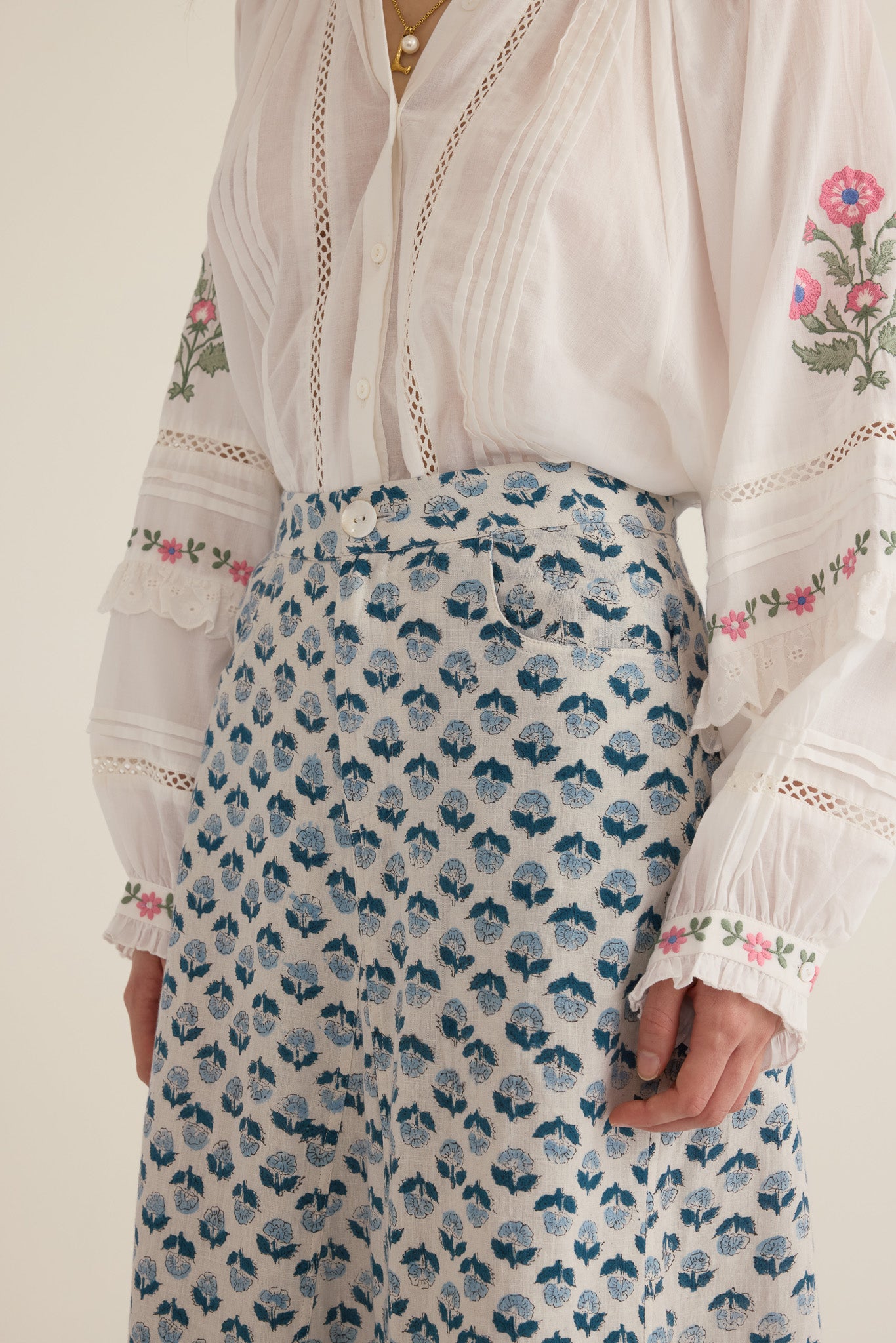 Closeup view of model wearing the Joni Block Printed Cotton A-Line Midi Skirt in Blue Gardenia with the Juliet Embroidered Raglan Drop Sleeve Blouse in Ivory, showing button and fly detail