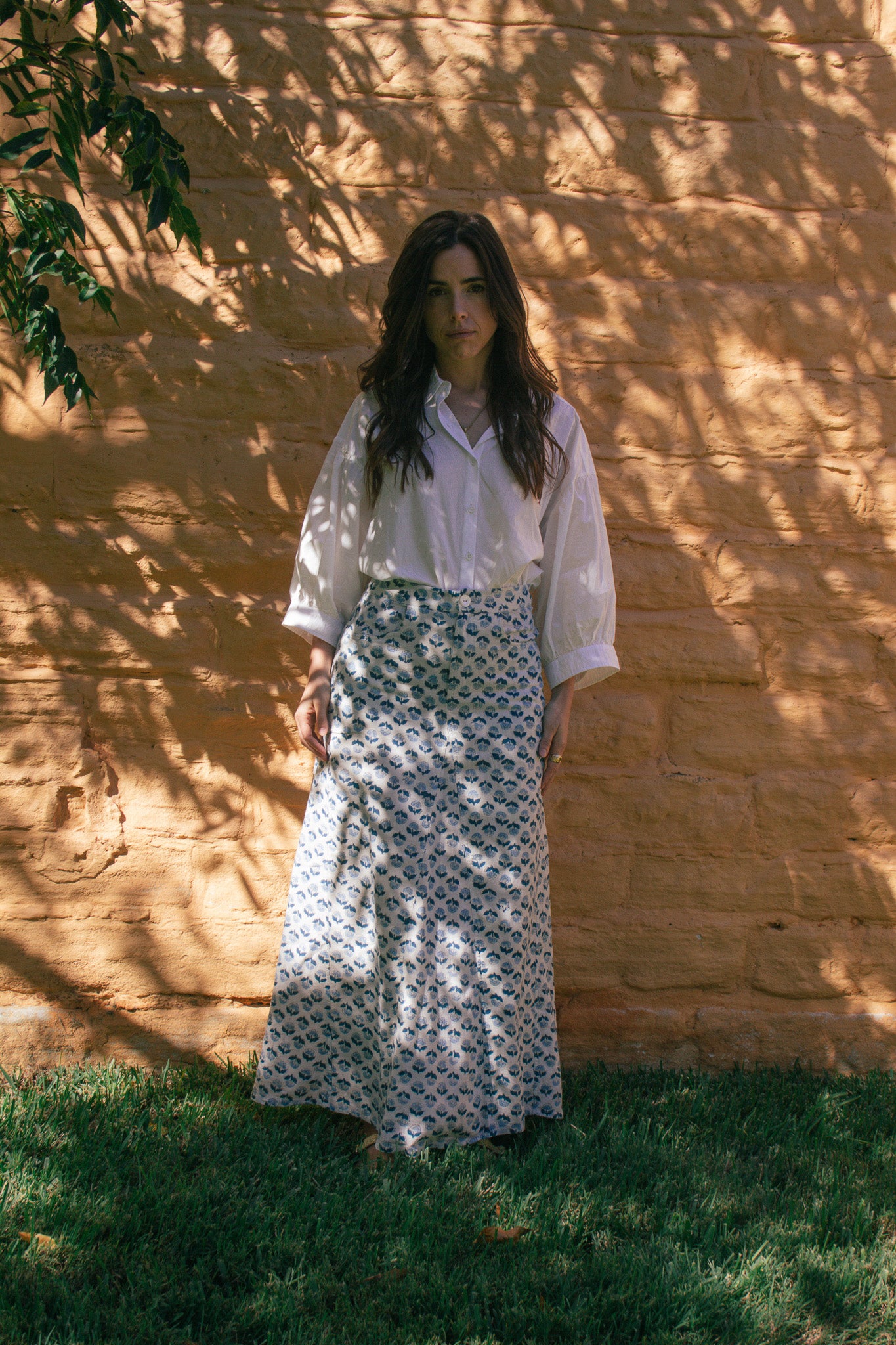 Model wears LAYLA POET romeo blouse in ivory organic cotton poplin with 3/4 wide cuff, with the Joni handblock printed midi skirt in blue and white ditsy print