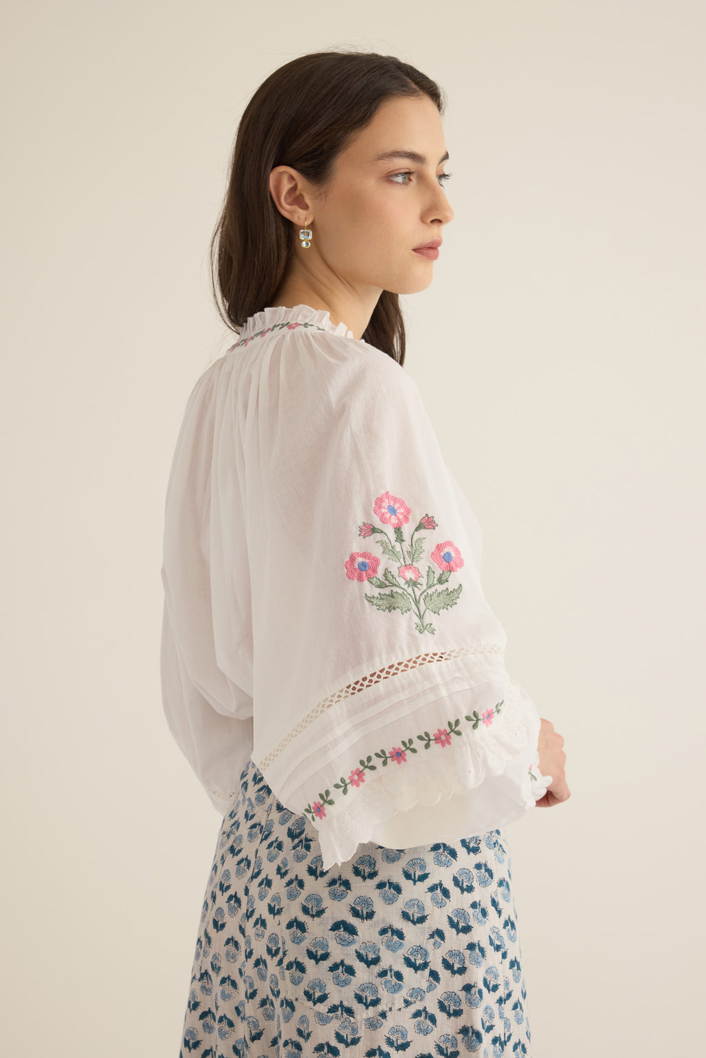 Side sleeve view of model with arms at hips wearing the Juliet Embroidered Cotton Juliet Drop Sleeve Raglan Shirt in Ivory with floral embroidered motifs, pintucking and lace detail, showing billowing sleeve detail