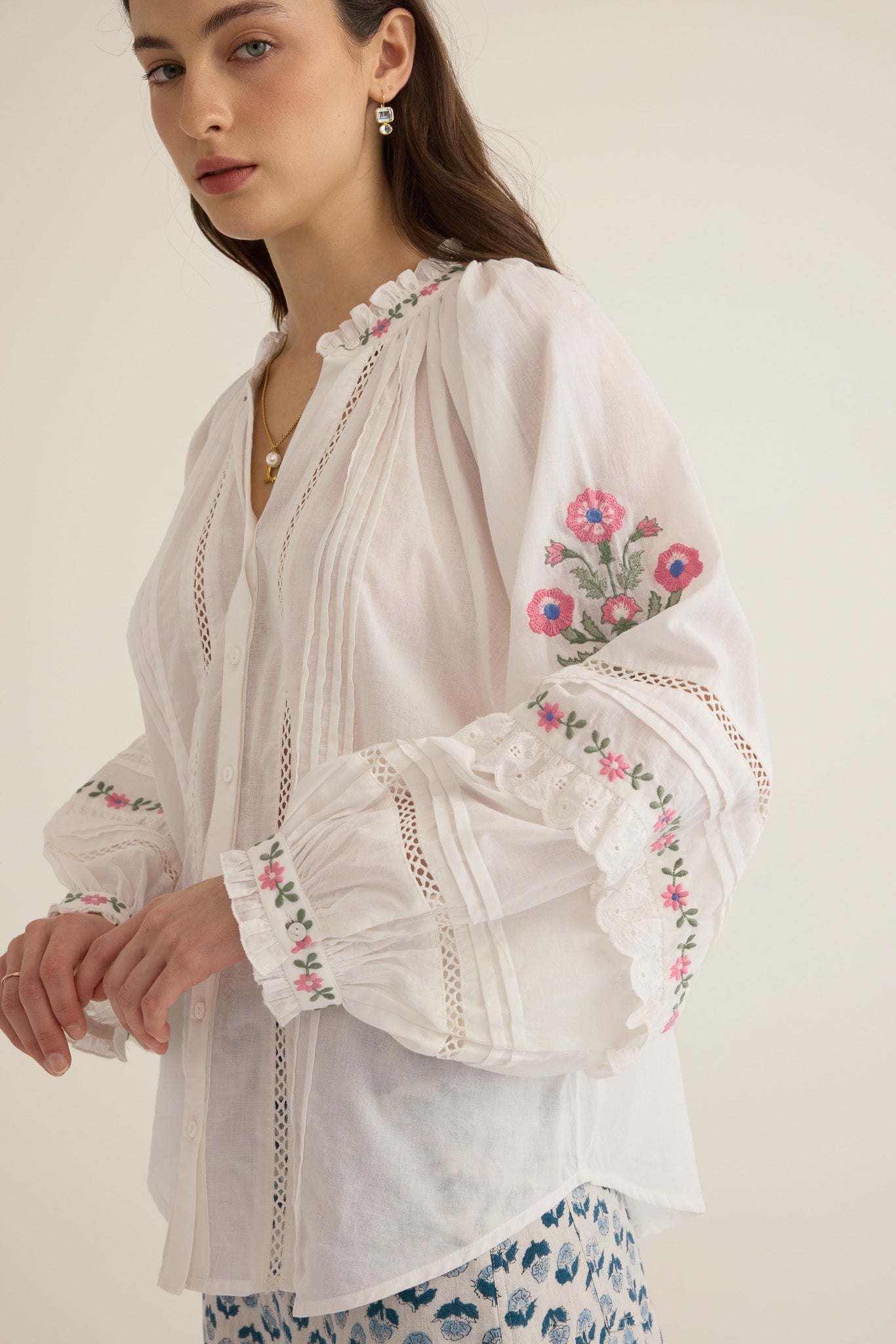 Side closeup view of model wearing the Juliet Embroidered Cotton Juliet Drop Sleeve Raglan Shirt in Ivory with floral embroidered motifs, pintucking and lace detail