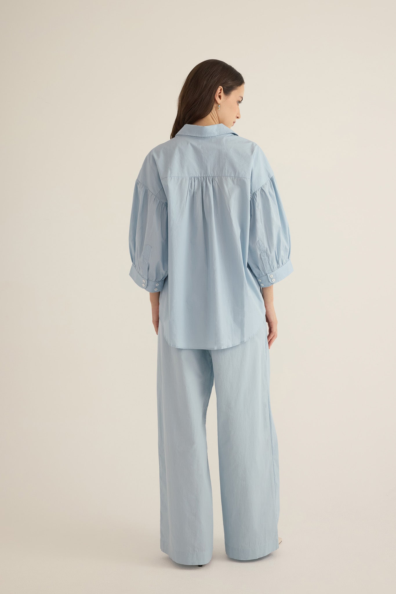 Back view of model wearing the Romeo wide cuff shirt and pleated pant in forget me not pale blue