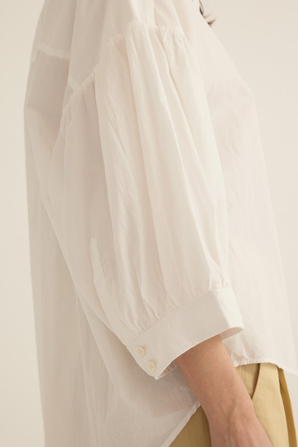 Side view of model wearing the Romeo wide cuff shirt in ivory organic cotton poplin