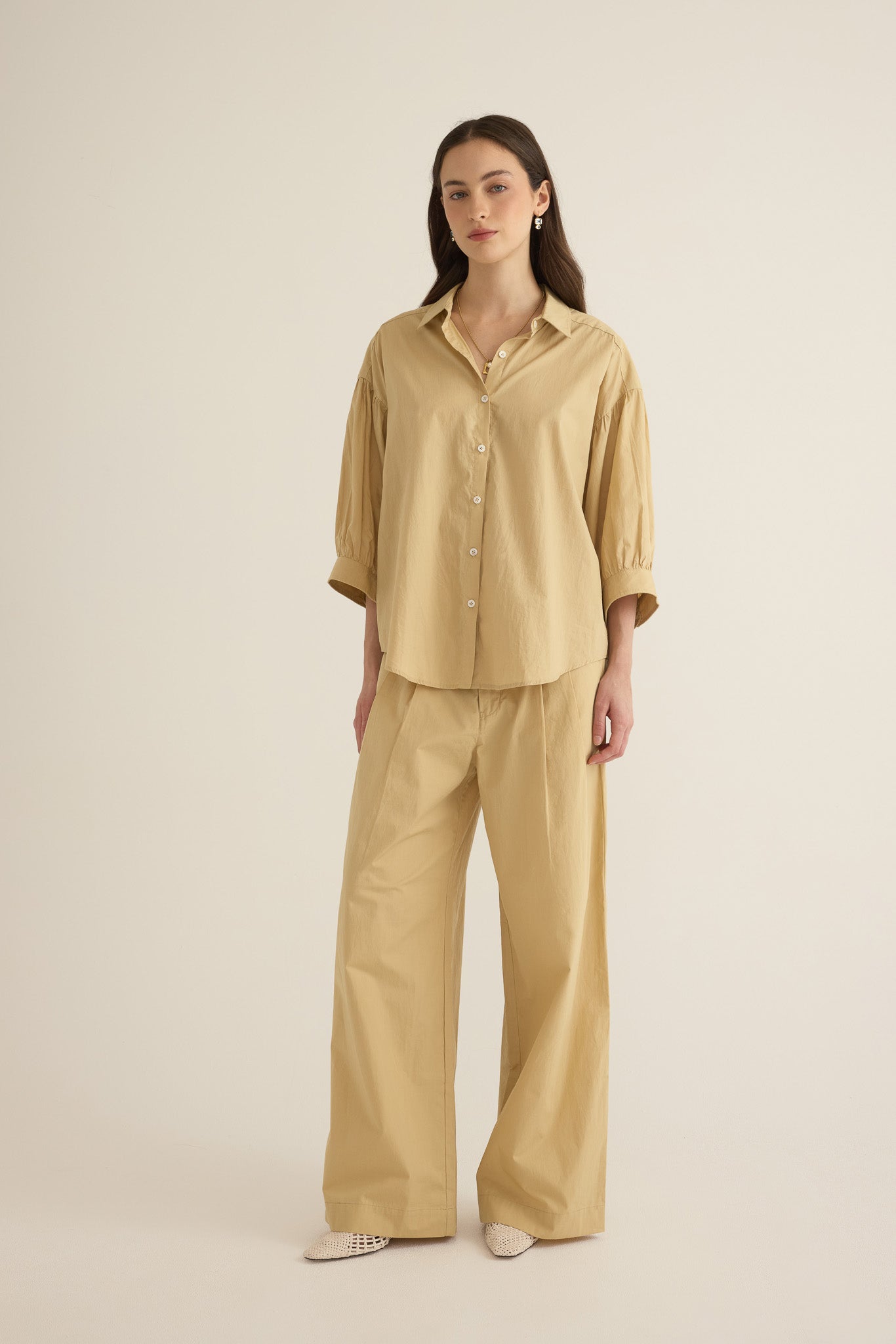 Model wearing the Romeo wide-leg pleat pant in light beige organic cotton, styled with the Romeo wide cuff shirt in taos taupe beige