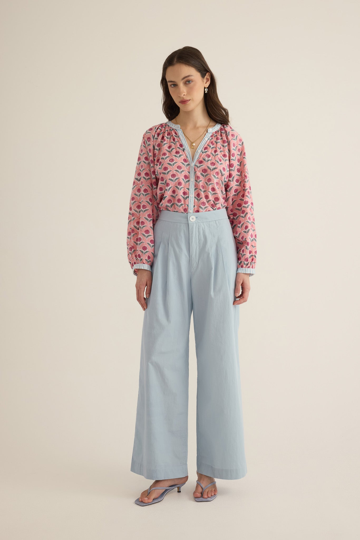 Model wearing the Romeo wide-leg pleat pant in pale blue organic cotton, styled with the Juliet block print pink and blue patterned shirt