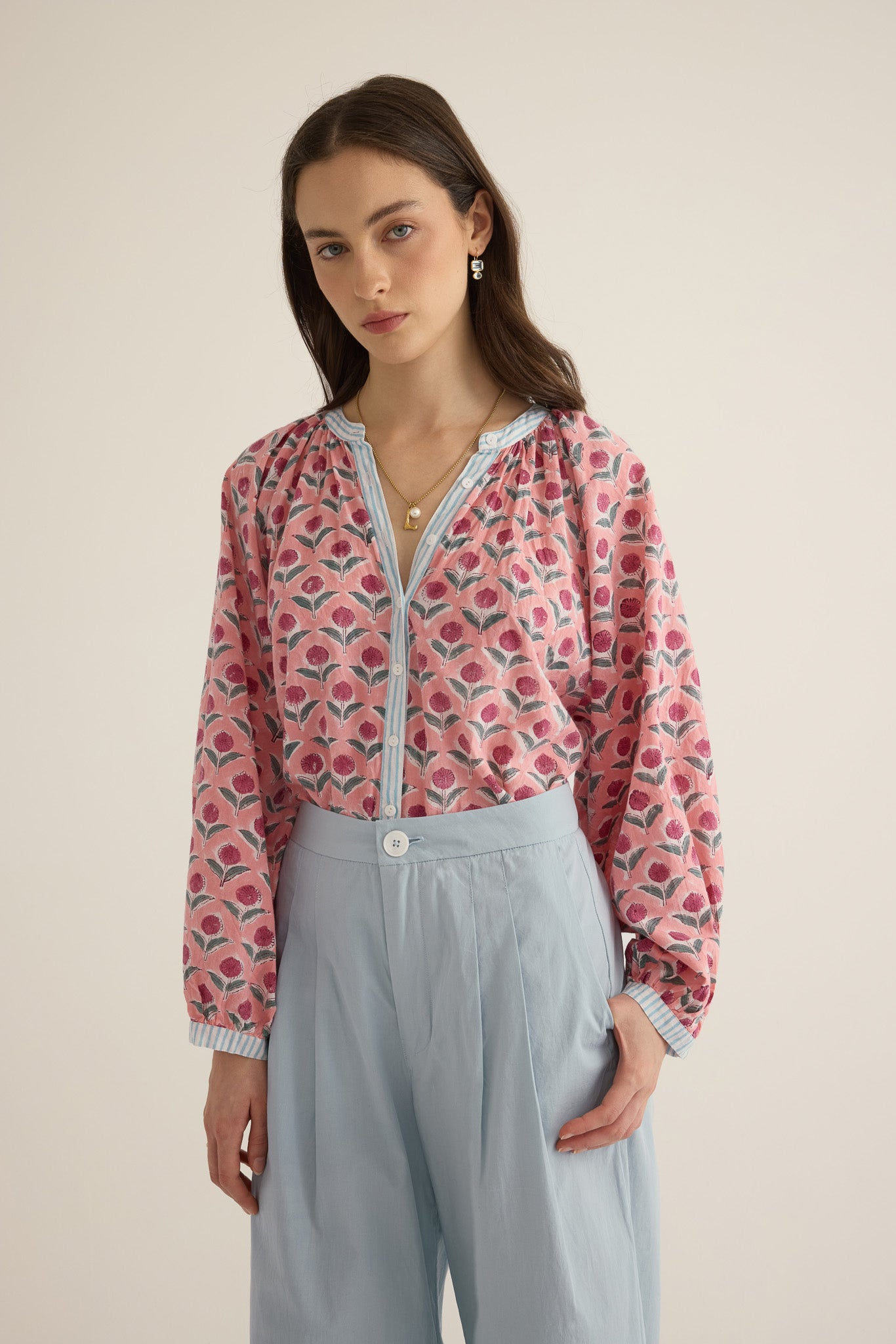 Close up of model wearing the Romeo wide-leg pleat pant in pale blue organic cotton, styled with the Juliet block print pink and blue patterned shirt