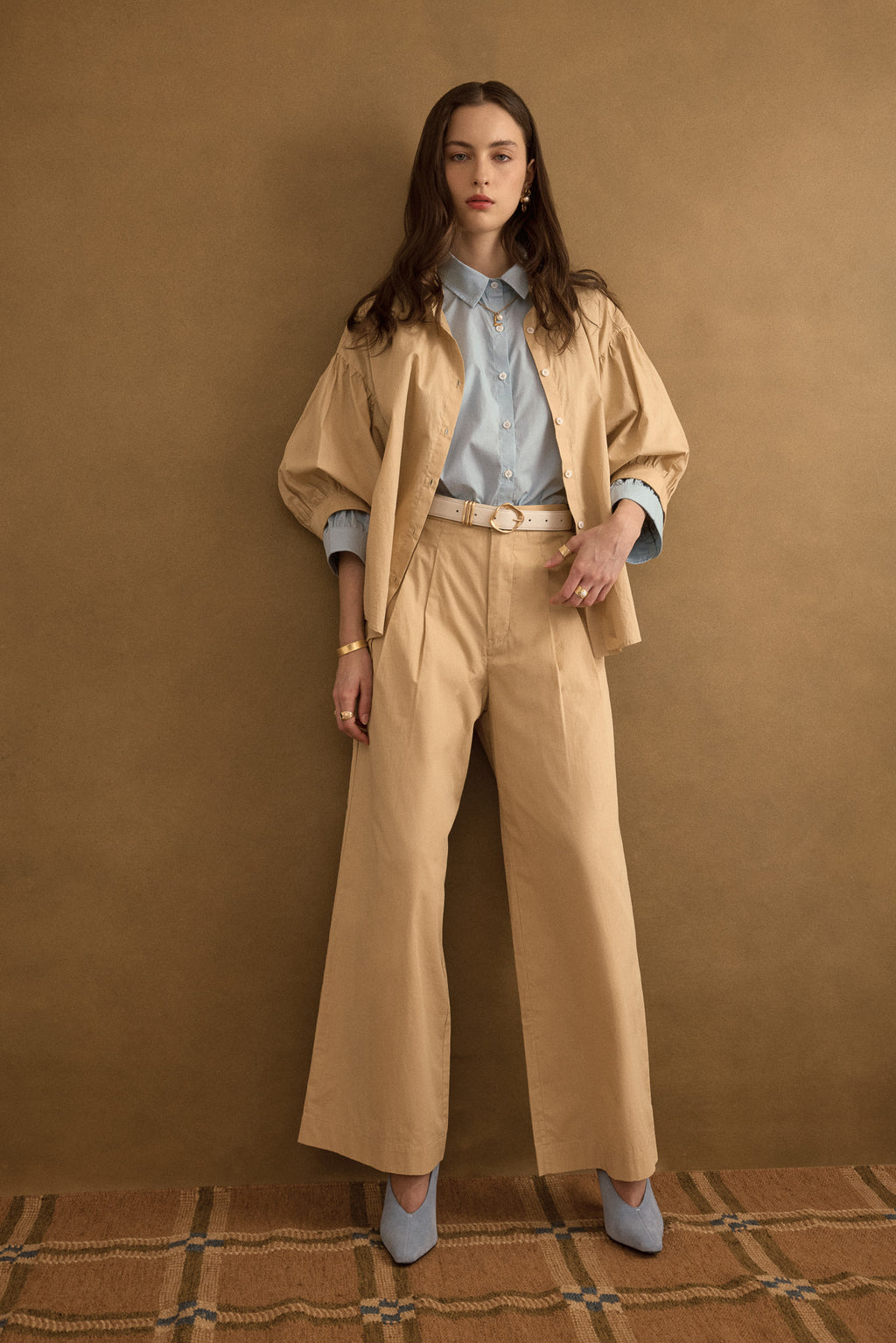 Model wearing the Romeo wide-leg pleat pant in light beige organic cotton, styled with the Romeo wide cuff shirt in taupe beige and forget-me-not blue