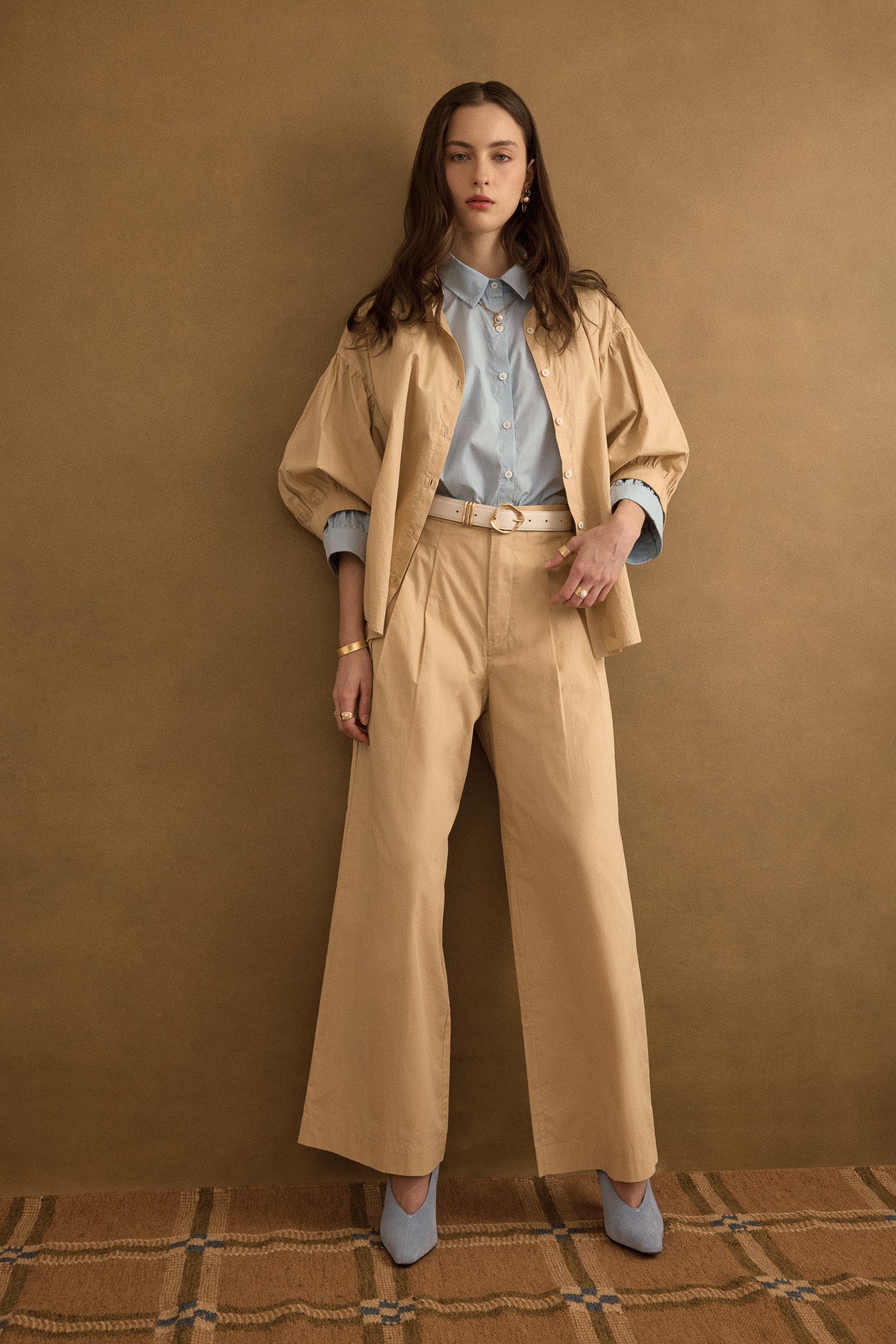 Model wearing the Romeo wide-leg pleat pant in light beige organic cotton, styled with the Romeo wide cuff shirt in taupe beige and forget-me-not blue