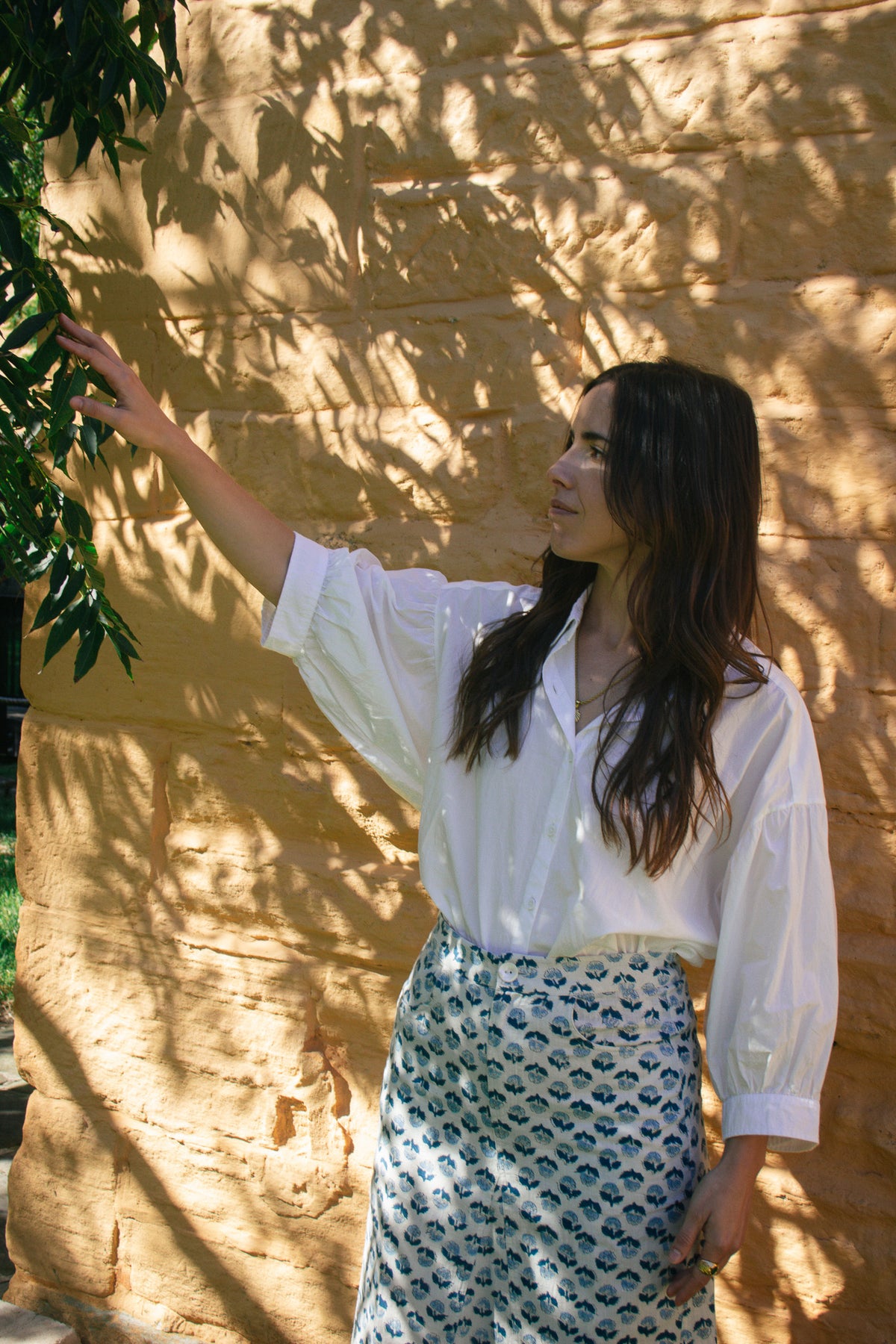 Model wearing LAYLA POET Romeo shirt in ivory white organic cotton poplin, with the handblock printed joni midi skirt, in a blue and white ditsy floral print.
